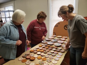 Three participants admire pottery pieces on a table.