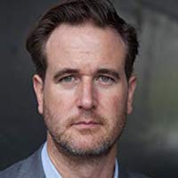 Photo of a man in a grey jacket.