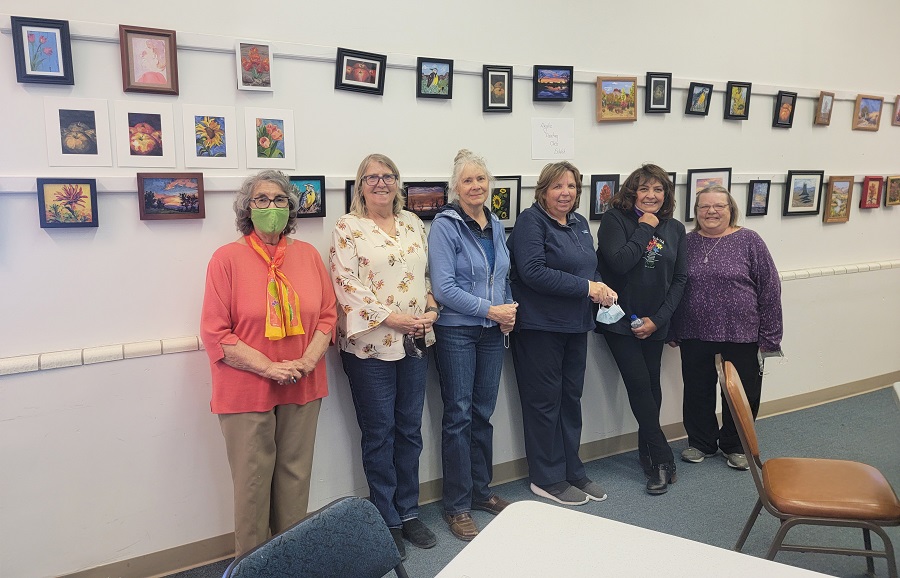 A photo of a group of participants from a program. They are posing for the camera, with paintings hung up on the wall behind them.